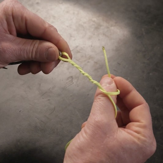 Hands wrapping a tag end around standing line.