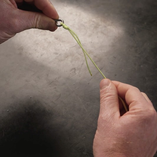 Hands firmly pull the tag end which tightens the fishing knot.