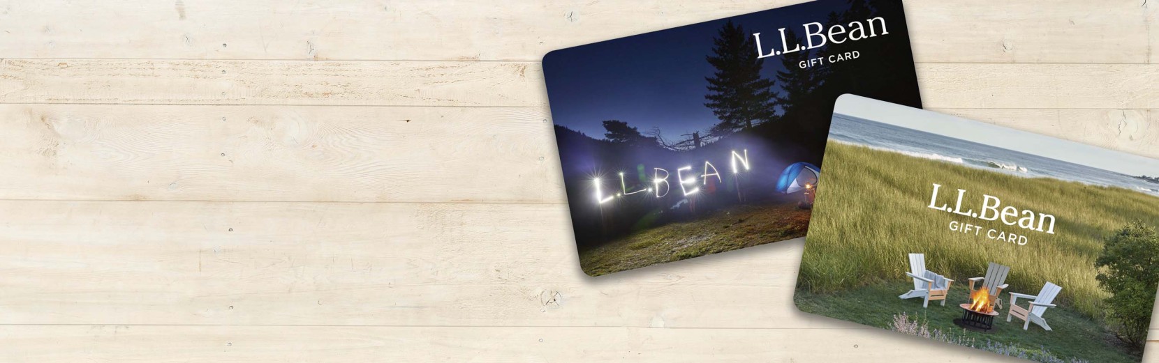 2 L L Bean gift cards on a light wood background.